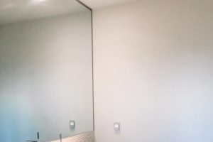 modern single white sink with shiny chrome tall fixture and wall length mirror
