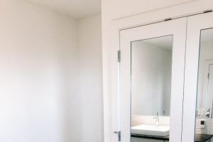 white modern bathroom with low tank toilet and mirrored doors