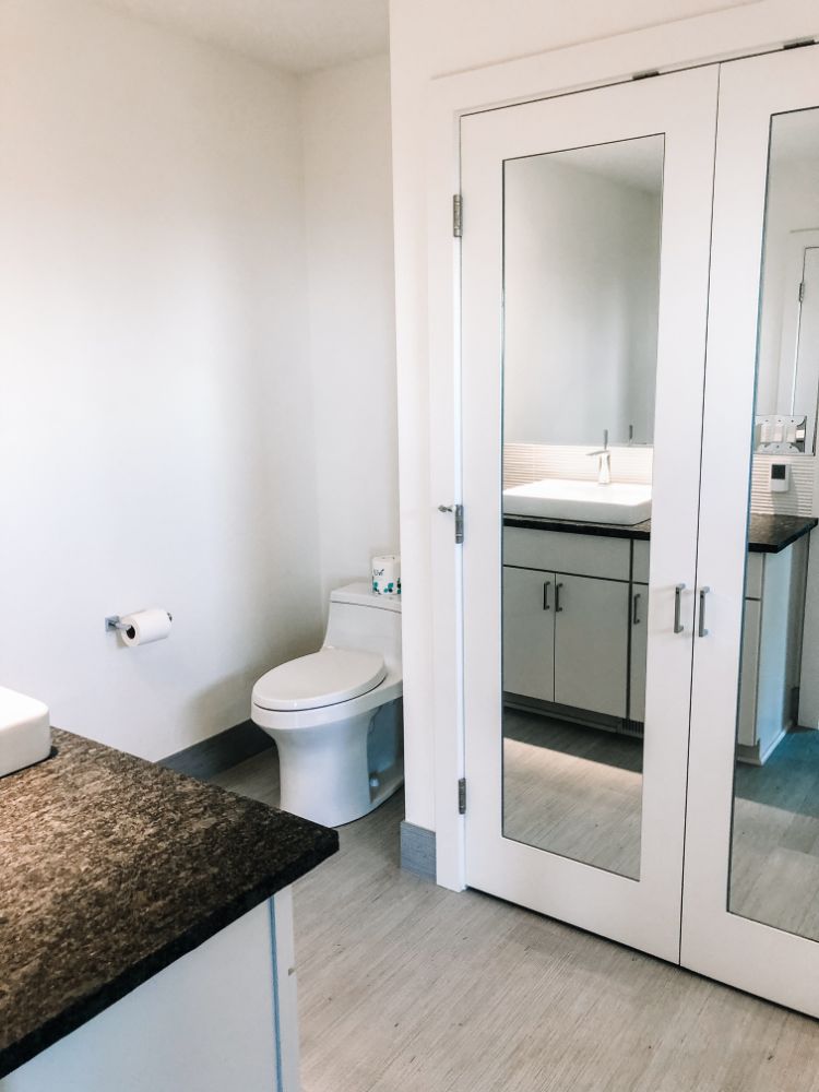 white modern bathroom with low tank toilet and mirrored doors