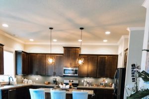 modern large kitchen with dark brown cabinets and white chairs and dark hardwood floors