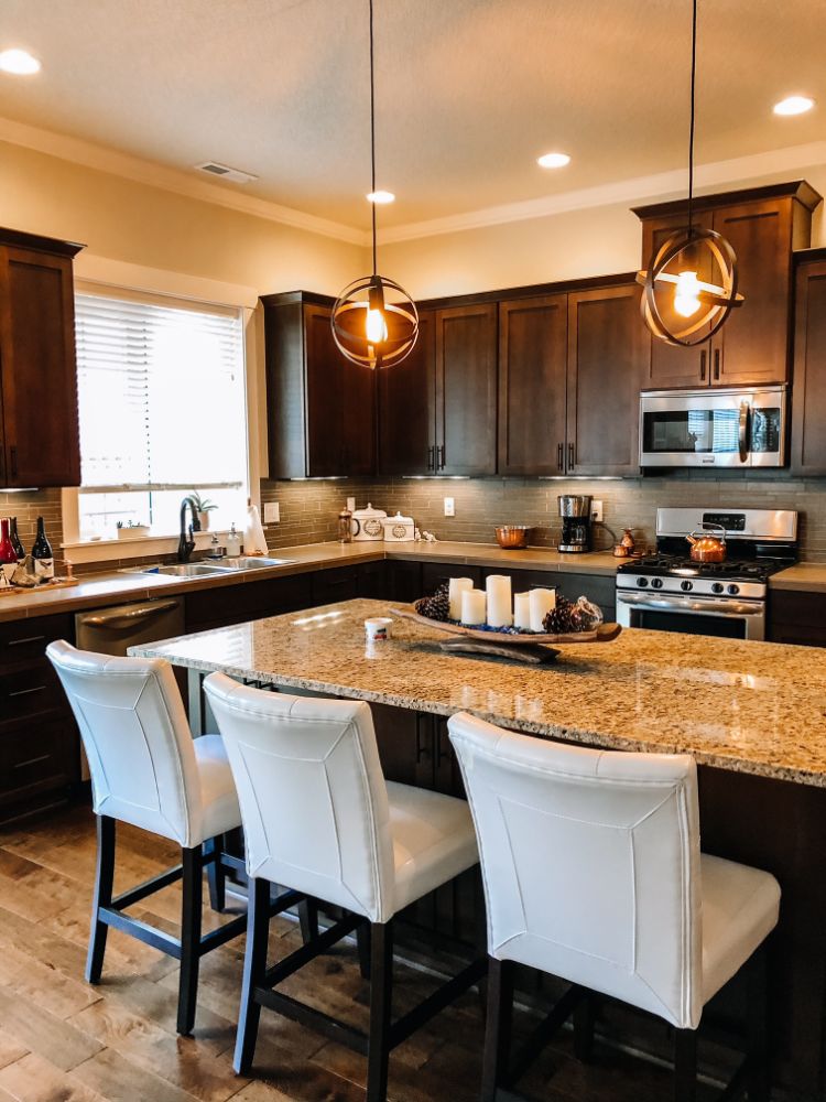 dark cabinets with granite countertops and white leather chairs