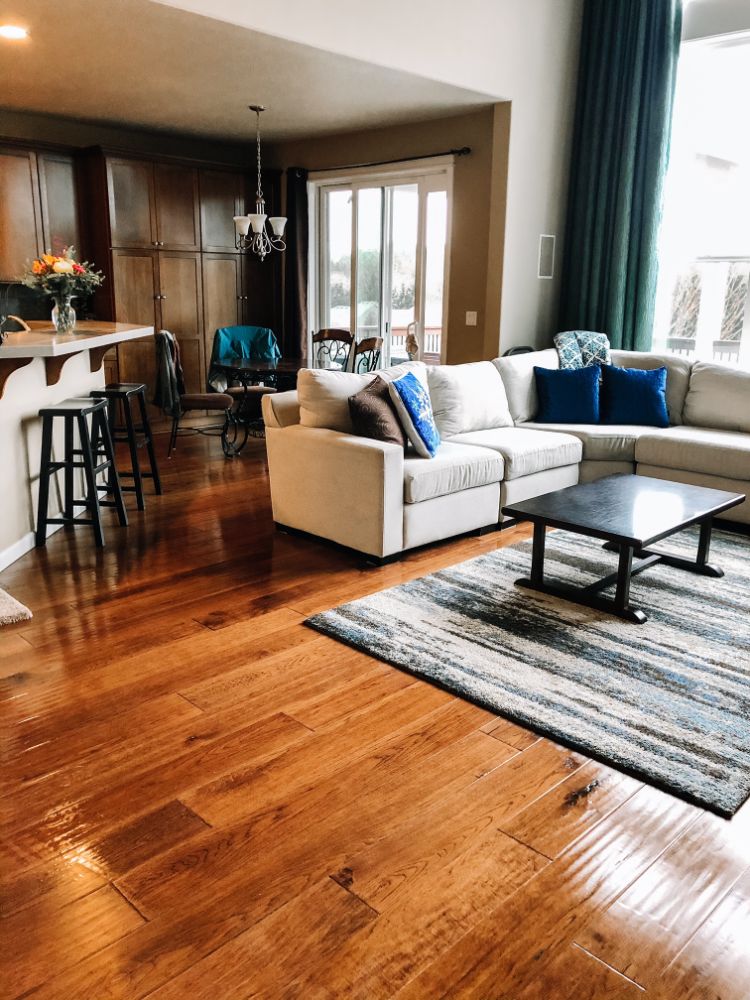 open layout with tan couch and rich brown hardwood floors